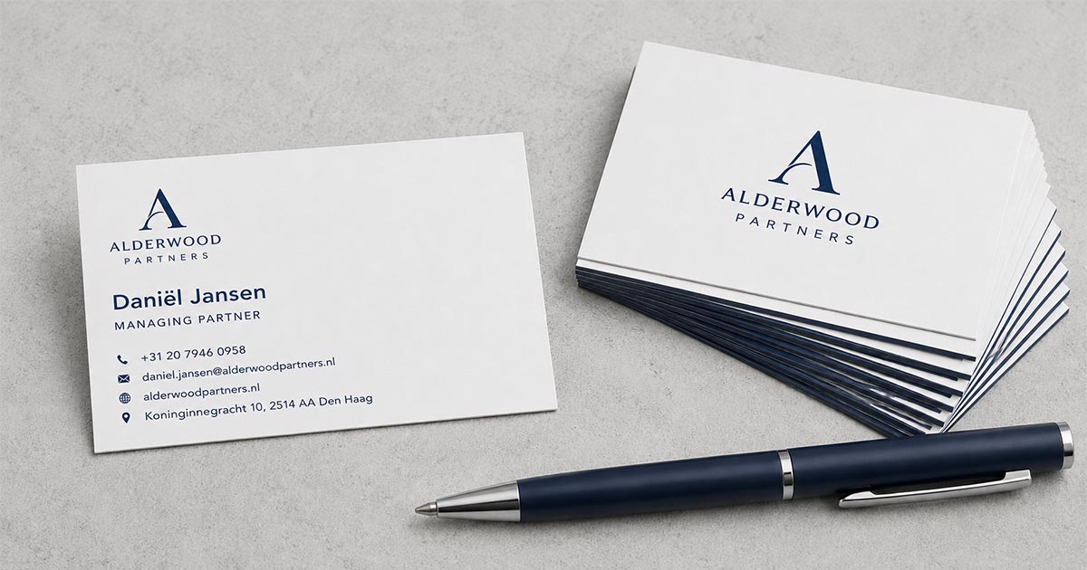Professioneel visitekaartje met logo, naam en contactgegevens, liggend naast een pen en stapel kaartjes